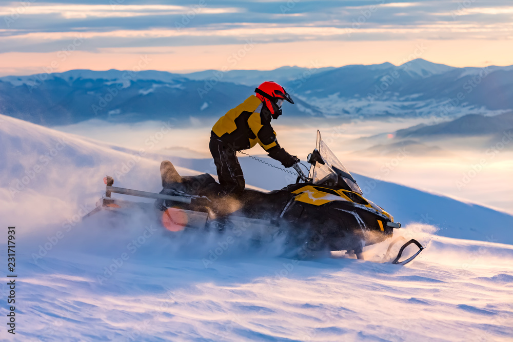 A man is ridind snowmobile in mountains.