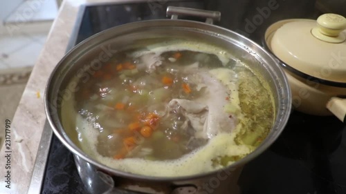 On the stove close up a pot of chicken soup.