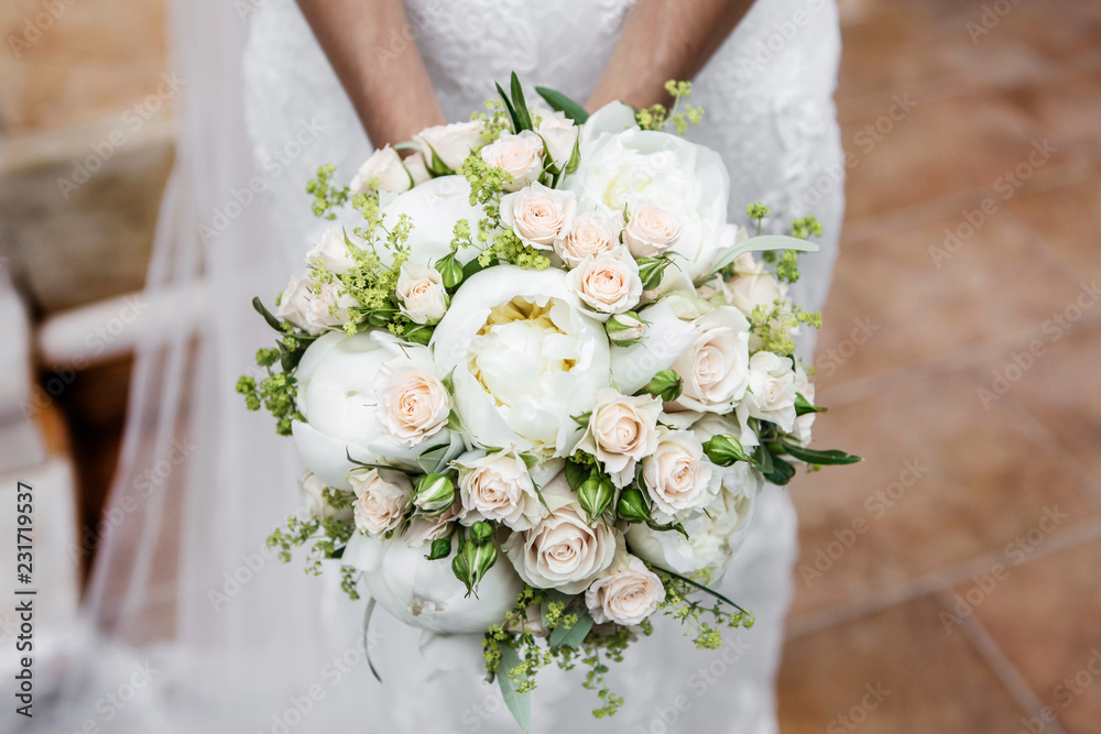 Dettaglio di Bouquet di peonie e rose ,tenuto in mano da una sposa in abito  color bianco Stock Photo