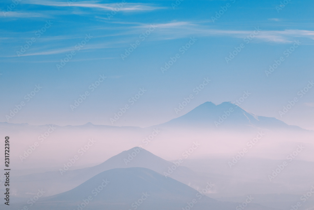 three mountains in the fog on the horizon
