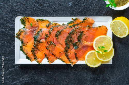 Gravadlax - Nordic dish of thinly sliced raw salmon cured in salt, sugar and dill and accompanied by dill and mustard sauce - top view photo
