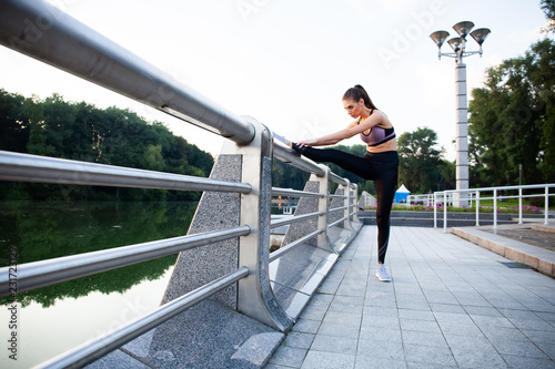 Portrait of fit and sporty young woman doing stretching in city.