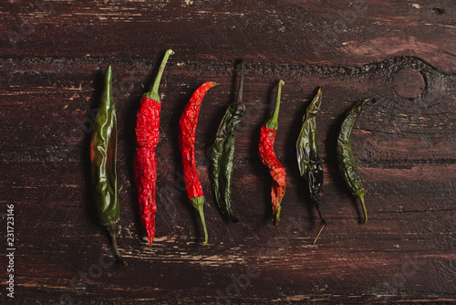 Dried hot red and green chili peppers on brown textured wood