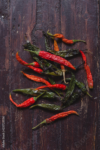 Dried hot red and green chili peppers on brown textured wood
