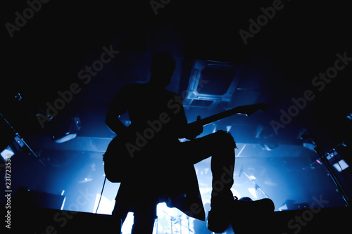 Guitarist silhouette in darkness on a stage in blue back lights playing solo