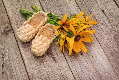 Fototapeta Naklejka Na Ścianę i Meble -  Summer still life with rudbeckia and straw bast shoes