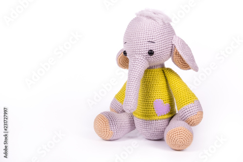 Little knitted baby elephant on white background. Baby elephant toy sitting on white background. Copy space