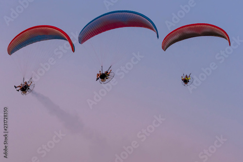 Three paramotors flying against the sky painted in the colors of a beautiful sunset photo