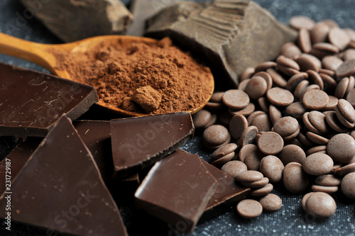 Various forms of chocolate. Bitter lump, milk chocolate in biscuits, cocoa powder, chocolate in a tile. Chocolate occupies the entire space of the frame. Close-up. Macro shooting.