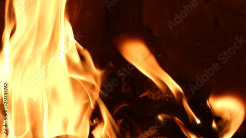 Paper with blurred text burning in fire. Closeup view of red hot glowing flame inside stove. Embers and documents in furnace or campfire.  Abstract background.