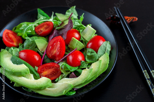 Wallpaper Mural Vegetable salad with avocado, cherry tomatoes, arugula and spinach on a black plate on a dark background. Torontodigital.ca