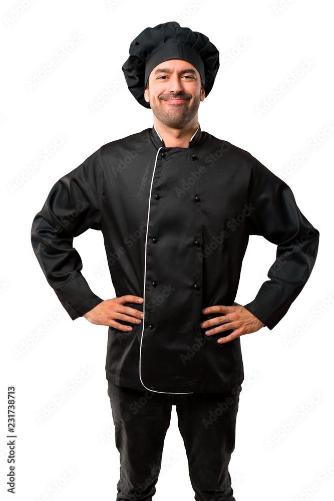 Chef man In black uniform posing with arms at hip and laughing looking to the front on isolated white background Chef man In black uniform posing with arms at hip and laughing looking to the front on isolated white background