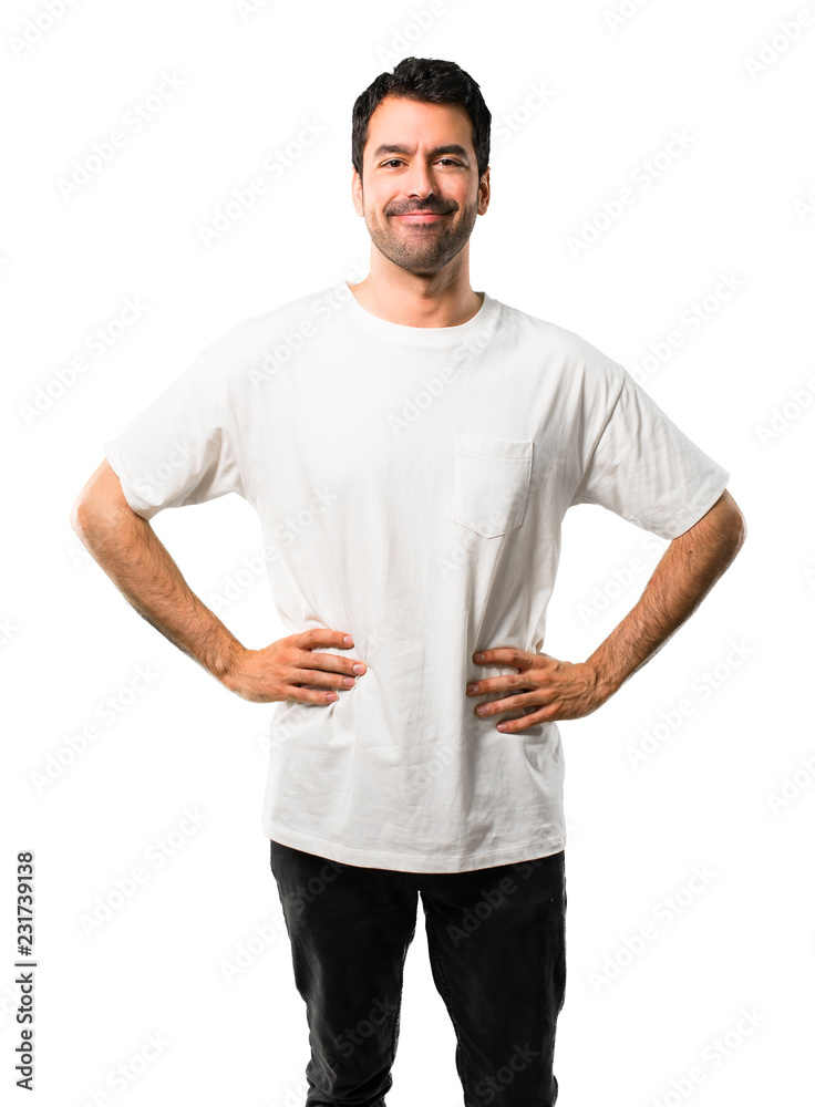 Young man with white shirt posing with arms at hip and laughing looking to the front on isolated white background