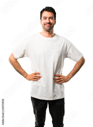 Young man with white shirt posing with arms at hip and laughing looking to the front on isolated white background