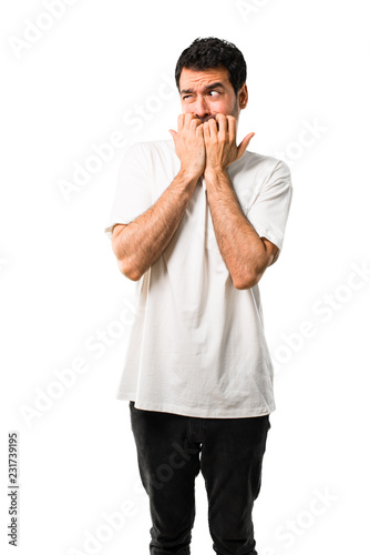 Young man with white shirt is a little bit nervous and scared putting hands to mouth on isolated white background © luismolinero