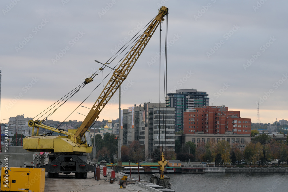 Repair of the bridge in the city, construction of the bridge, crane on the bridge. Lifting equipment. Panorama of the city. 