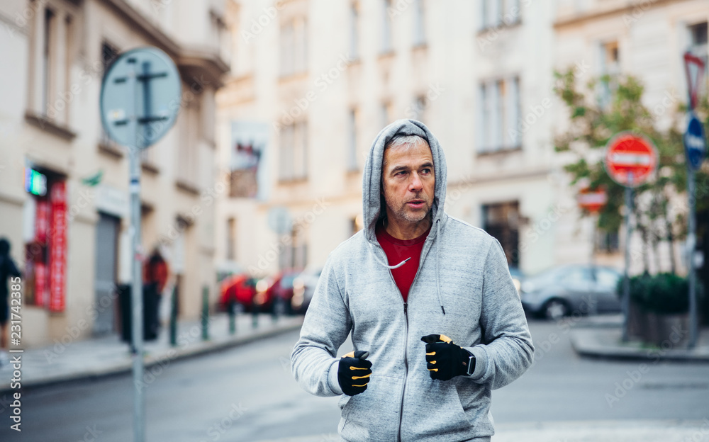 Mature male runner running outdoors on the street in Prague city.