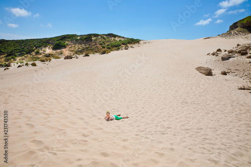 little girl lying on sand under the dune in horizon