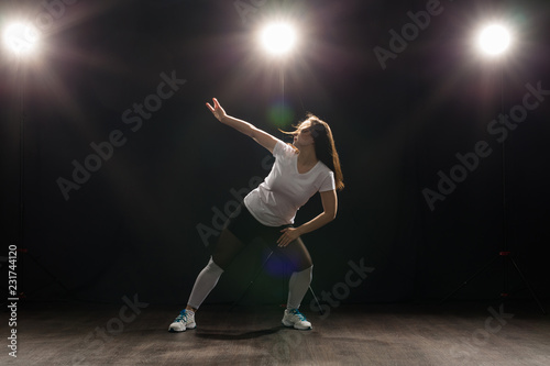 Dance, hip-hop, jazz funk and people concept - flexible young woman dancing in the darkness under the light