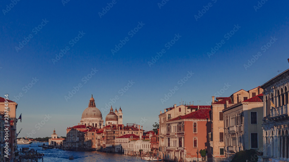 Basilica of Santa Maria della Salute and Venetian houses under blue sky at sunset, in Venice, Italy