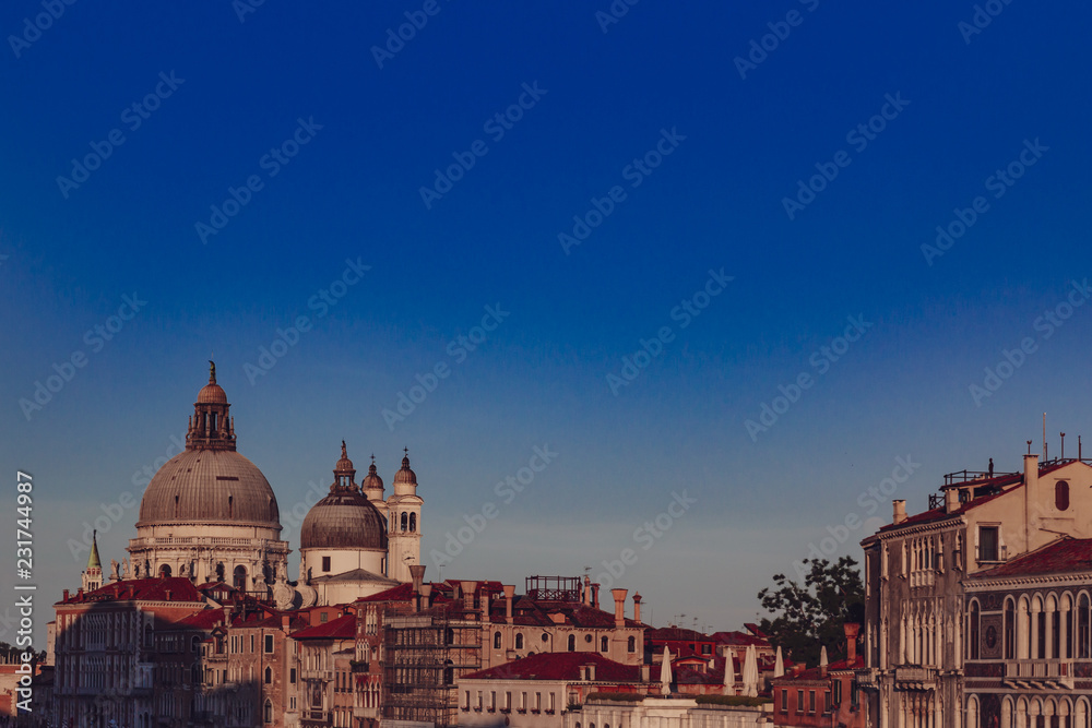 Basilica of Santa Maria della Salute and Venetian houses under blue sky at sunset, in Venice, Italy