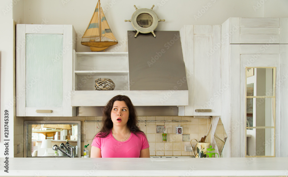 Housewives, emotions and people concept - Surprised young woman in the kitchen at home Housewives, emotions and people concept - Surprised young woman in the kitchen at home