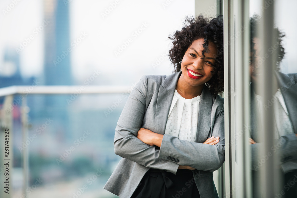 A portrait of a businesswoman standing on a terrace, arms crossed. - obrazy, fototapety, plakaty 