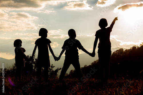 Silhouette group children looking sunset on mountain