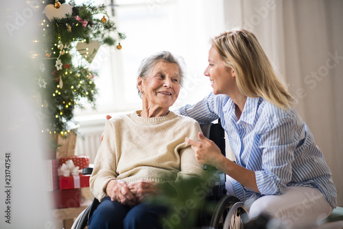 A senior woman in wheelchair with a health visitor at home at Christmas time.