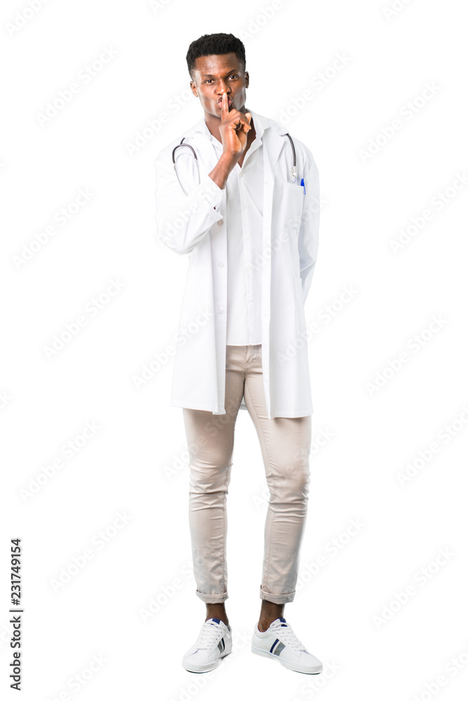 Full body of African american doctor showing a sign of closing mouth and silence gesture putting finger in mouth on white background Full body of African american doctor showing a sign of closing mouth and silence gesture putting finger in mouth on white background