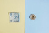 Bitcoins and Zloty on a pastel background, the concept of confrontation between cryptocurrency and paper money