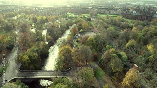 Aerial footage over Kelvingrove park in Glasgow. A bridge over the river Kelvin and people walking in the park. photo