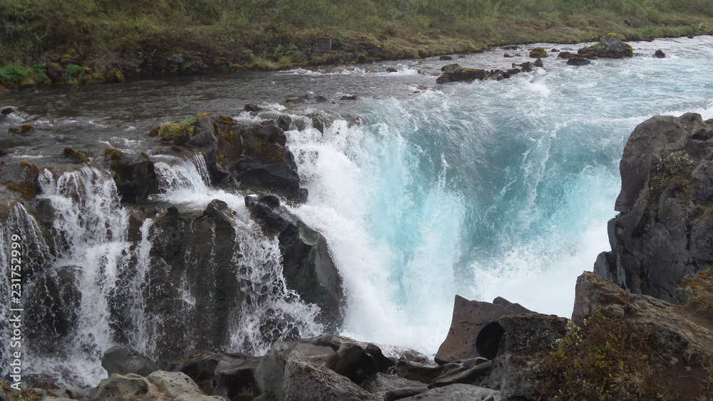 Isländischer Wasserfall mit Felsen und türkisfarbigem Wasser