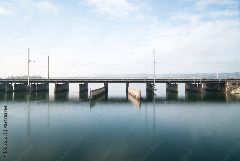 concrete bridge over water with a train line and road running parallel and a boat and ship passageway below