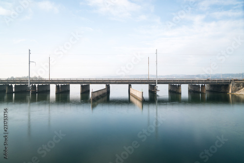 concrete bridge over water with a train line and road running parallel and a boat and ship passageway below