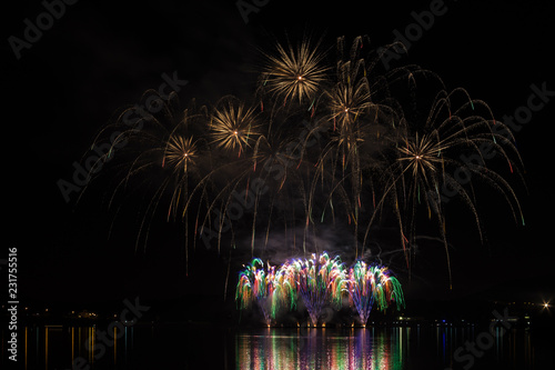 Rich and colorful fireworks over surface of Brno's Dam with lake reflection