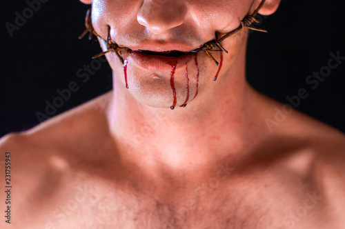 barbed wire  in the mouth  portrait on black background  blood on face
