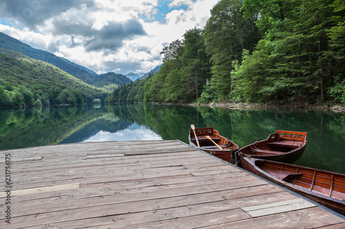Eevergreen forest on the Biogradskoe lake from wooden pier with rowboat. Biogradska Gora national park. Montenegro, Europa