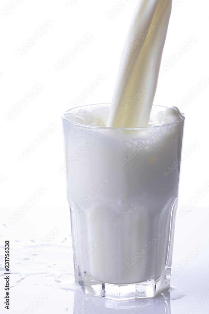 pouring a glass of milk creating splash on a white background pouring a glass of milk creating splash on a white background
