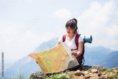 Young woman backpacker reading map  on hiking trip