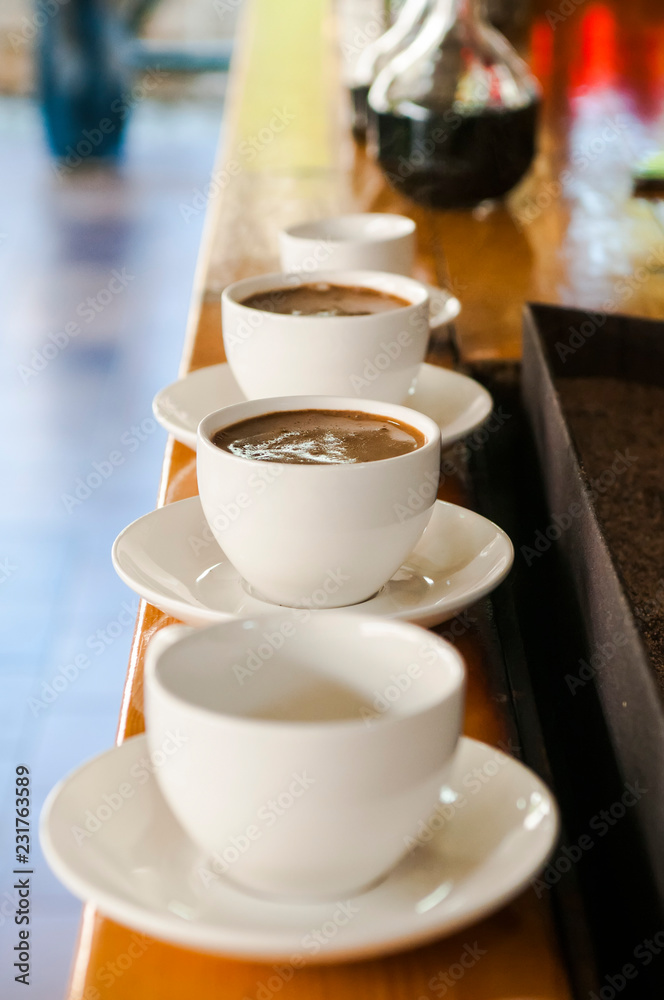 row of white cups with coffee with