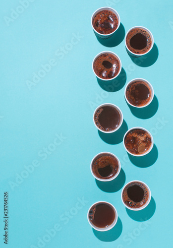 Vertical series of coffee cups on blue background with copy space