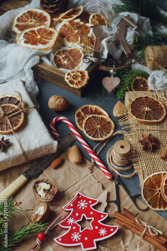 Christmas or New Year composition with handmade gifts, dry oranges, cinnamon, fir tree on dark stone table. Holidays preparations, hugge concept, selective focus