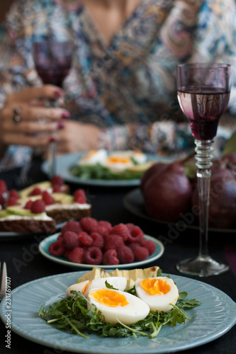 A light summer dinner for two: boiled eggs with arugula and avocado, raspberries for dessert, purple pears and white wine.