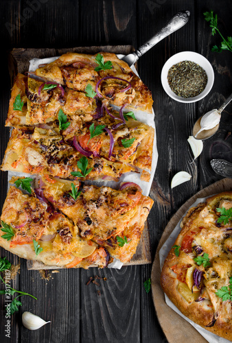 Delicious and appetizing pizza from yeast dough. Delicious and healthy vegetable pizza. Vegetable pizza on a black wooden table.