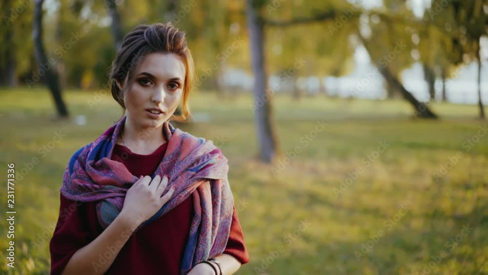 A portrait of a girl that`s posing to a camera in autumn park. A portrait of a girl that`s posing to a camera in autumn park.