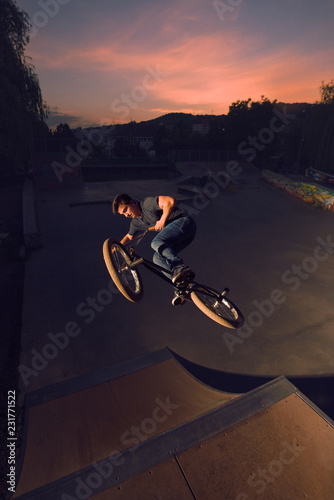 Teenager riding BMX perfoming midair stunts on ramp photo