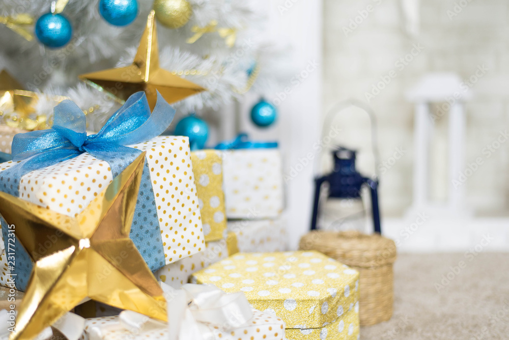Fototapeta premium family holiday concept. Merry Christmas and Happy Holidays. Studio with Christmas decor. Winter home decor. Christmas tree, fireplace with firewood Boxes with gifts and golden and blue bows. Xmas