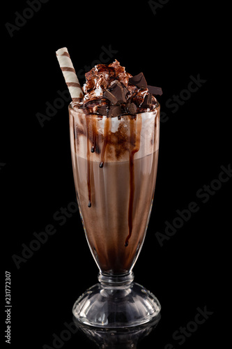 Fotografia Closeup glass of chocolate milkshake decorated with caramel and whipped cream isolated at black background