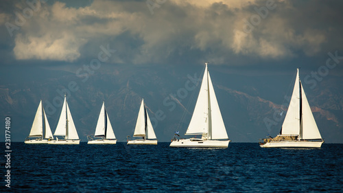 Fototapeta Naklejka Na Ścianę i Meble -  Sailing boats participate in yachting regatta among Greek islands in the Aegean Sea in stormy weather.